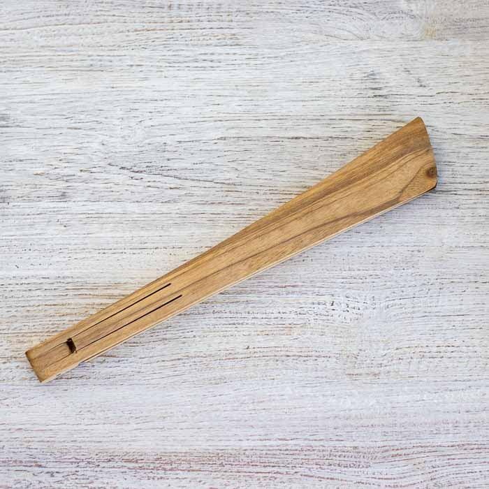 Pegador articulado de madeira de Bali sobre superfície rústica clara.