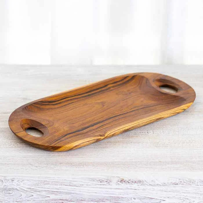 Bandeja artesanal em madeira teca com alças vazadas e design oval orgânico.