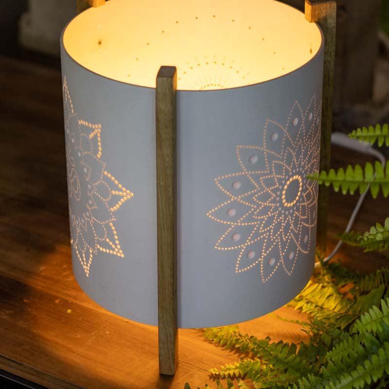 Abajur cilíndrico decorativo com design geométrico espiritualizado posicionado em mesa de cabeceira.