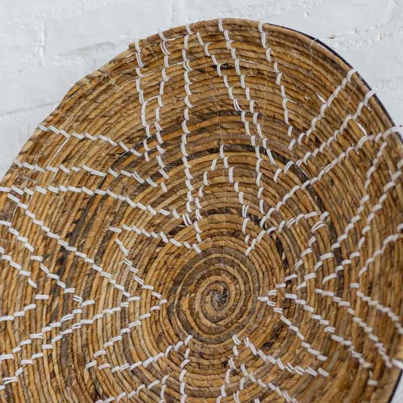 Detalhe do trançado espiral e costura manual em cestaria de parede Matahari importada da Indonésia.