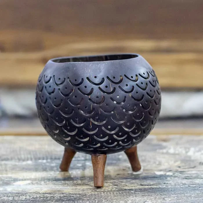 Porta-vela de coco com desenhos vazados que criam sombras delicadas 