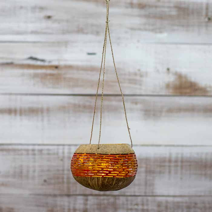 Porta-vela artesanal flutuante com padrões vazados que projetam luz e sombra. 