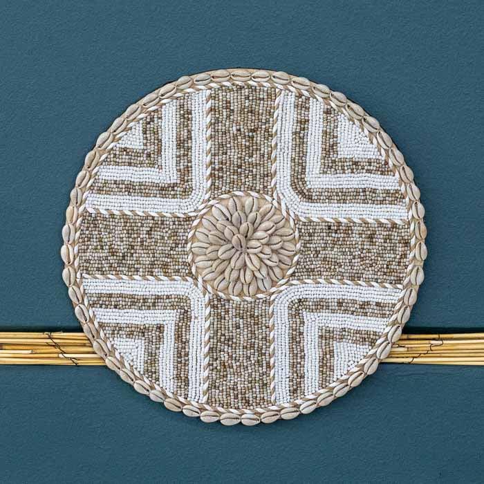 Objeto decorativo com conchas brancas e formas circulares, inspirado na estética balinesa. 