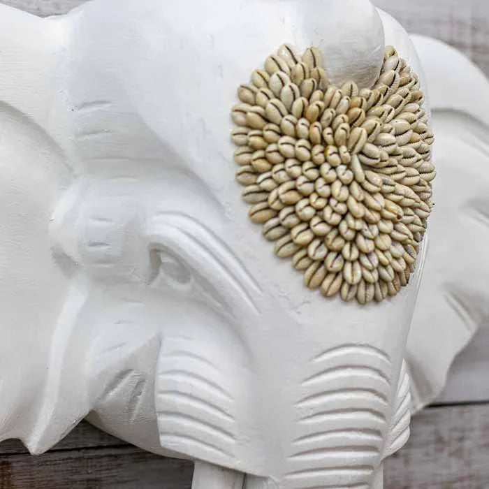 Decoração étnica de luxo com escultura de elefante em pátina branca sobre parede de madeira rústica.