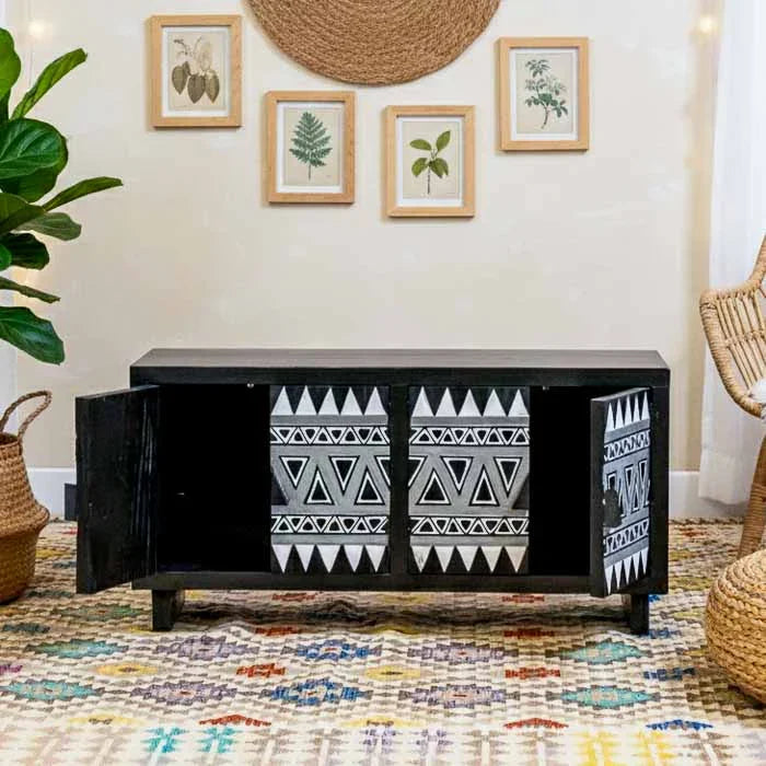 Móvel aparador de 120cm com entalhes manuais em tons de preto e branco em ambiente de sala sofisticada.