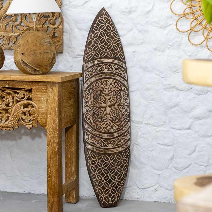 Prancha étnica em madeira entalhada manualmente por artesãos de Timor, com desenhos tribais em espiral e formas geométricas que simbolizam harmonia e ancestralidade. 