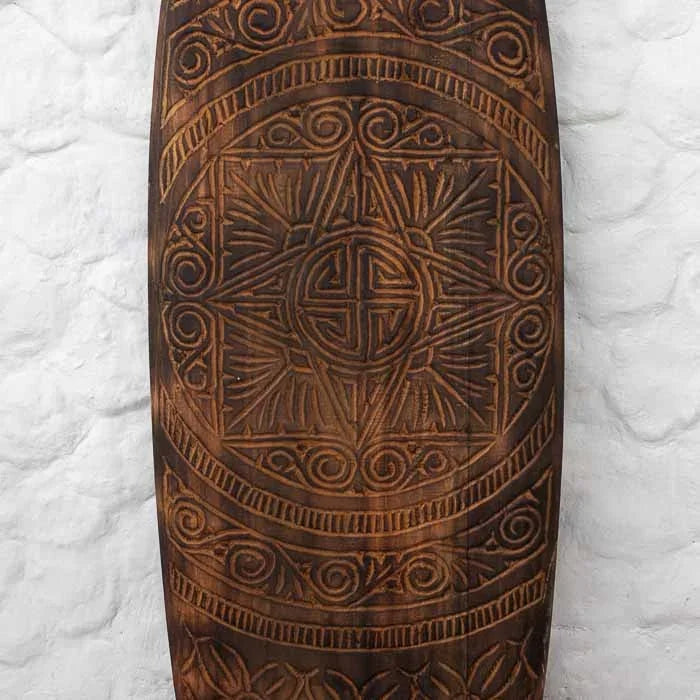 Prancha artesanal de Timor com gravuras tribais detalhadas e tons terrosos, representando a tradição cultural e o valor simbólico do artesanato asiático. 