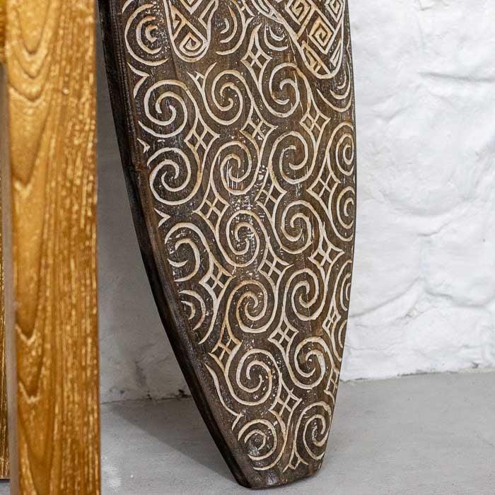 Arte em madeira artesanal de Timor com entalhes inspirados em símbolos étnicos, exibindo textura rústica e design autêntico do Sudeste Asiático. 