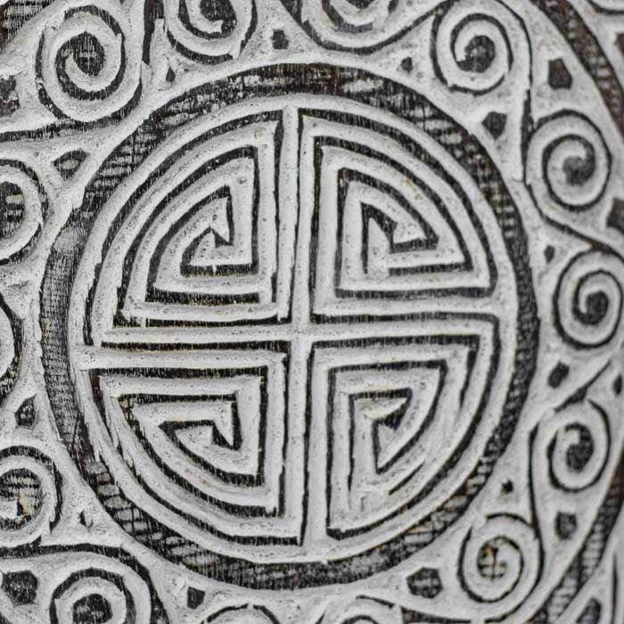 Painel artesanal com entalhes simbólicos, representando cultura e espiritualidade indonésia. 