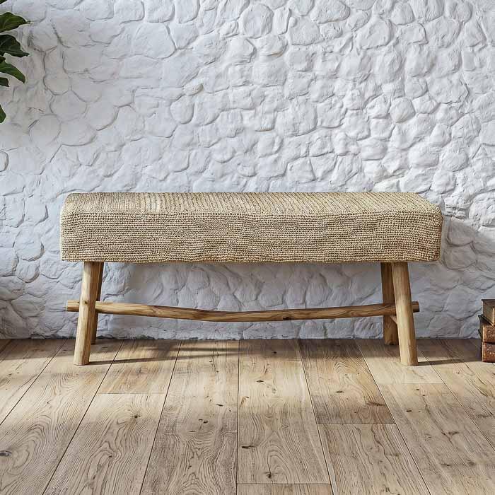 Banco artesanal de três lugares em rattan natural com estrutura de madeira clara em estilo balinês.