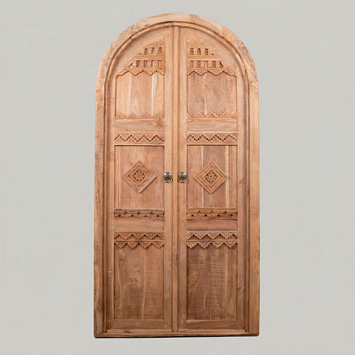 Porta de duas folhas com puxadores de argola em metal e padrões florais esculpidos manualmente.