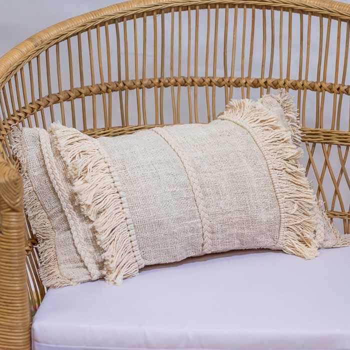 Almofada retangular artesanal em algodão natural, com franjas nas laterais.