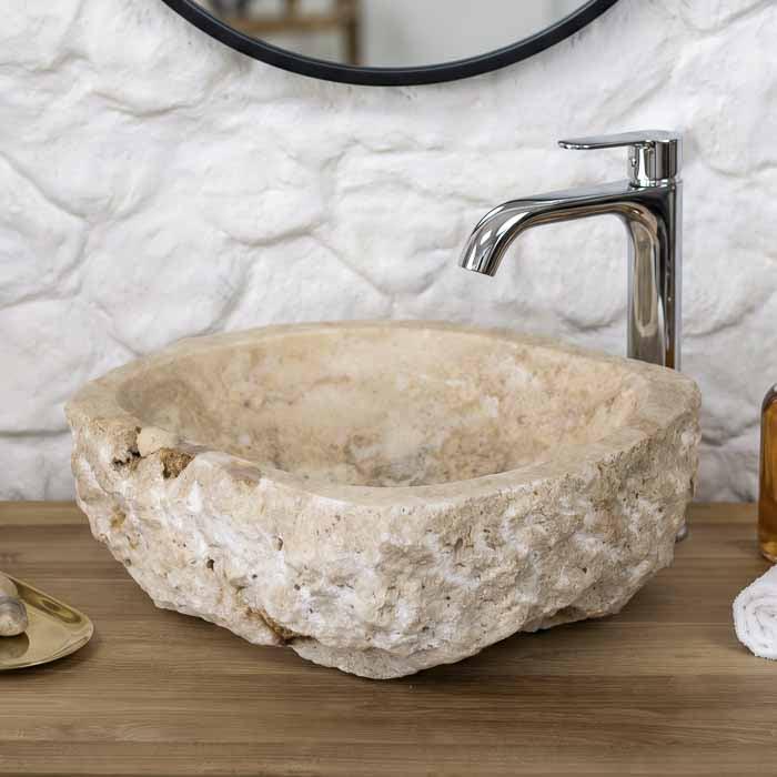 Cuba de pia artesanal esculpida em pedra ônix natural de Bali instalada sobre bancada de madeira nobre para lavabo. 