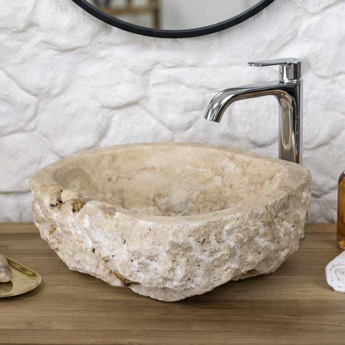 Cuba de pia artesanal esculpida em pedra ônix natural de Bali instalada sobre bancada de madeira nobre para lavabo. 