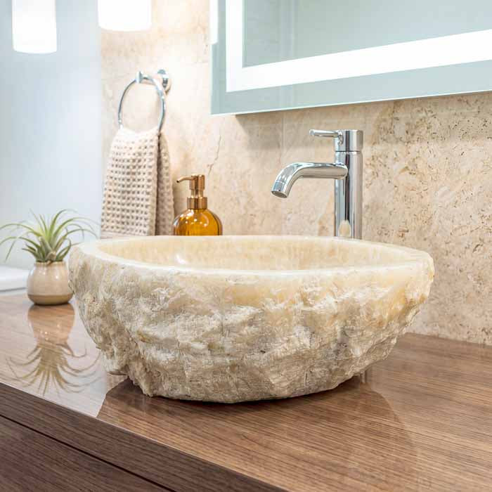 Cuba de pedra natural para lavabo combinando a elegância do ônix com bancadas rústicas e torneiras modernas. 