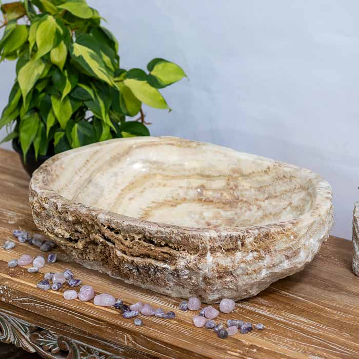 Cuba de pia artesanal em pedra natural, com veios dramáticos em tons de bege e marrom. 