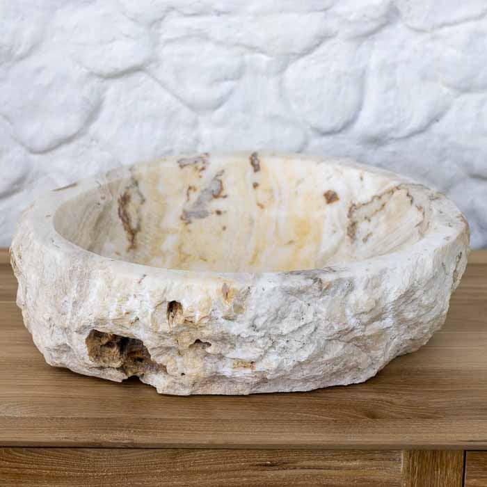 Pia de lavabo esculpida à mão em Bali, com interior polido e camadas minerais visíveis. 