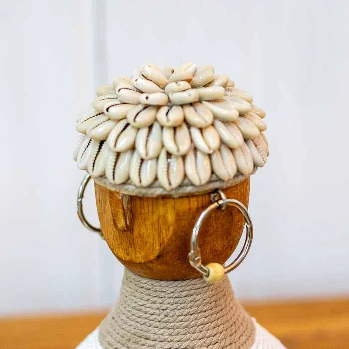 Boneca decorativa de Bali com base adornada por búzios e traços tribais minimalistas. 
