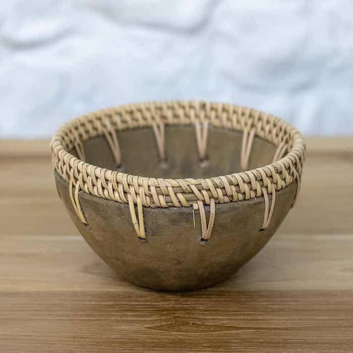 Cachepô decorativo de barro queimado artesanal com acabamento fosco e trançado de fibra natural na borda.
