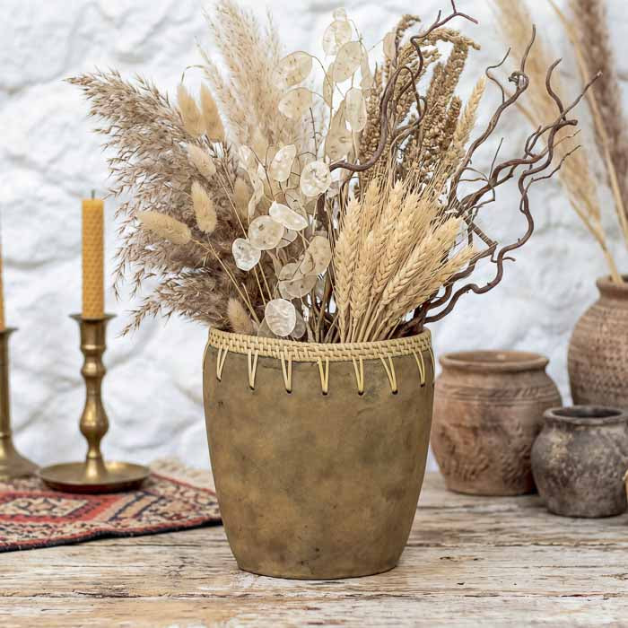 Vaso de cerâmica terrosa artesanal com acabamento fosco e costuras aparentes em fibras de rattan.