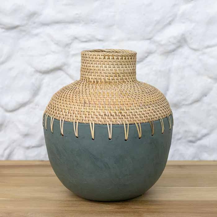 Vaso bojudo artesanal em terracota cinza com topo trançado em rattan natural de Bali sobre mesa.
