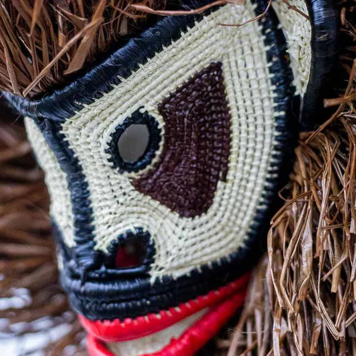 Objeto tribal de colecionismo étnico destacando a técnica de tecelagem manual em máscara de animal. 