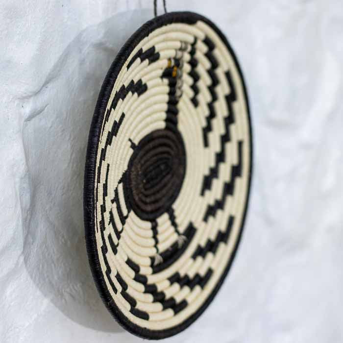 Detalhe da trama fechada e minuciosa de cesta de parede artesanal feita com folhas de palmeira do Panamá. 