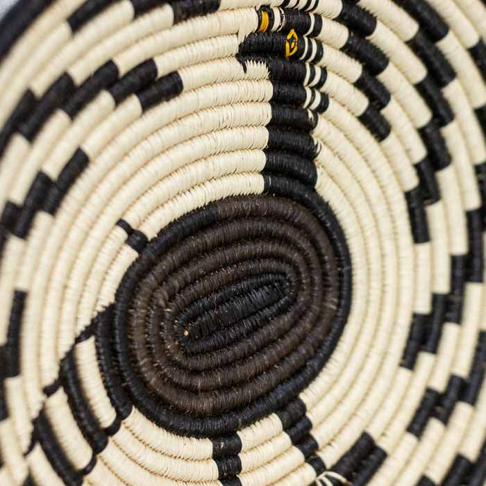 Cesta decorativa rasa modelo Mutum destacando o padrão circular inspirado em aves da floresta tropical. 