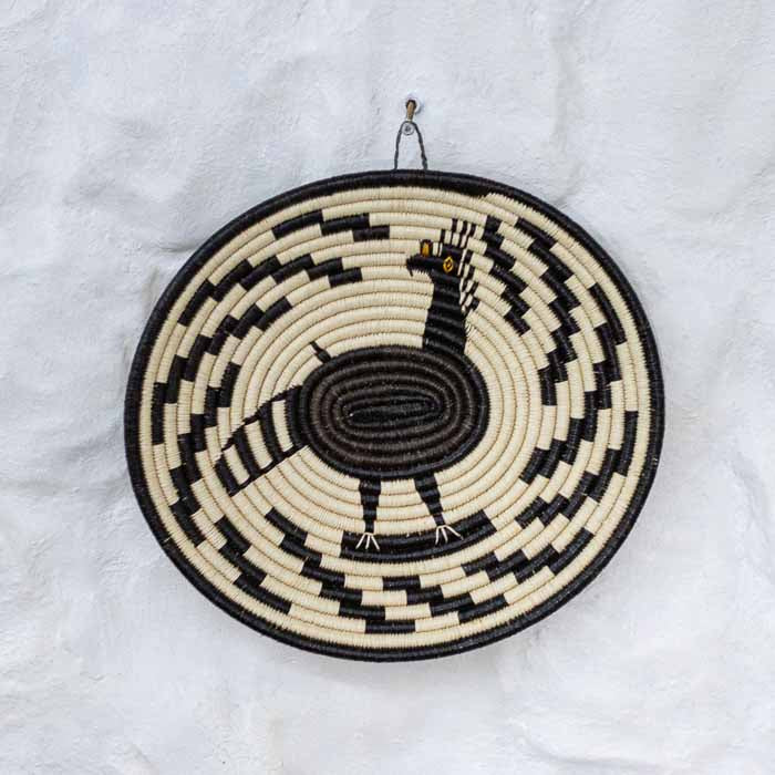 Prato de cestaria indígena tecido à mão em fibra de chunga com grafismos geométricos da etnia Emberá-Wounaan. 
