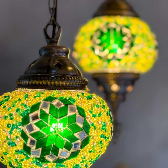Detalhe de lustre pendente artesanal da Turquia com cúpulas multicoloridas iluminadas em ambiente aconchegante. 