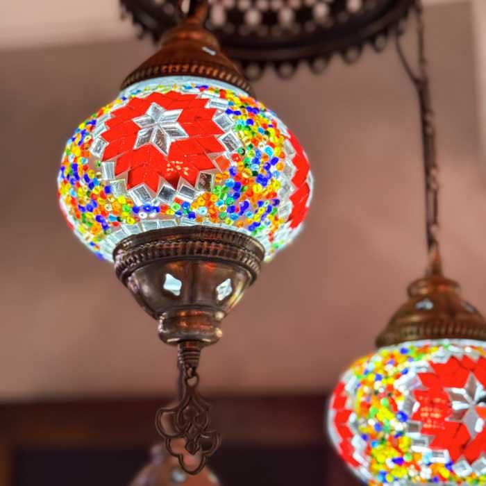 Luminária pendente turca com três globos de mosaico dispostos em alturas diferentes para um efeito visual dinâmico. 