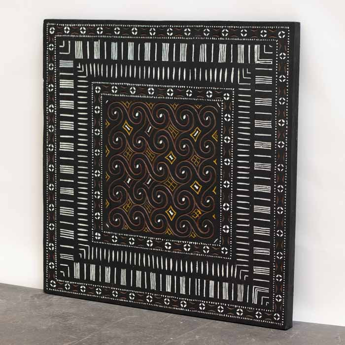 Detalhe central de grafismos ancestrais entalhados e pintados à mão em painel étnico de Bali.