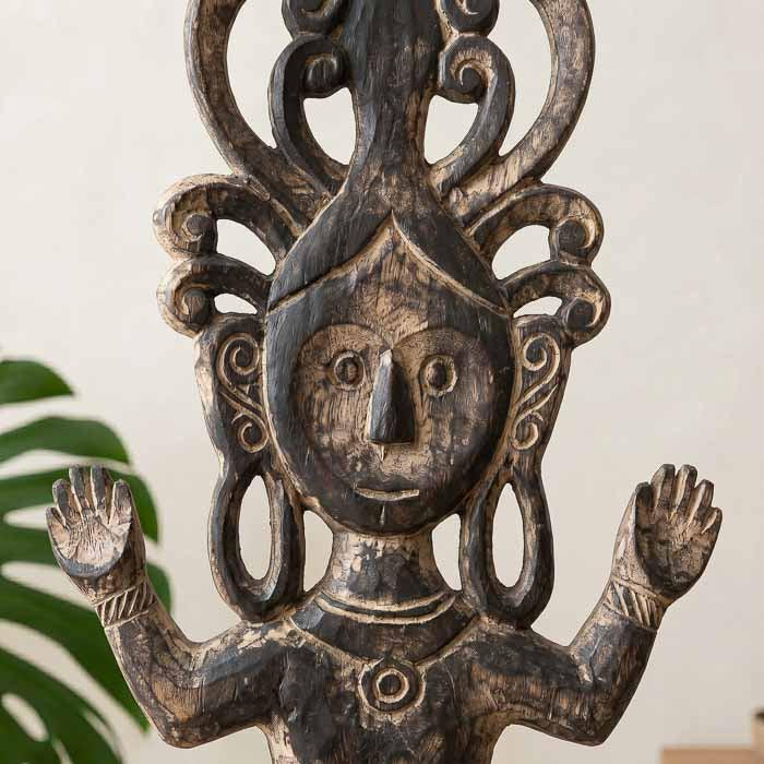 Detalhe do rosto estilizado e padrões rústicos em totem de madeira indonésio.