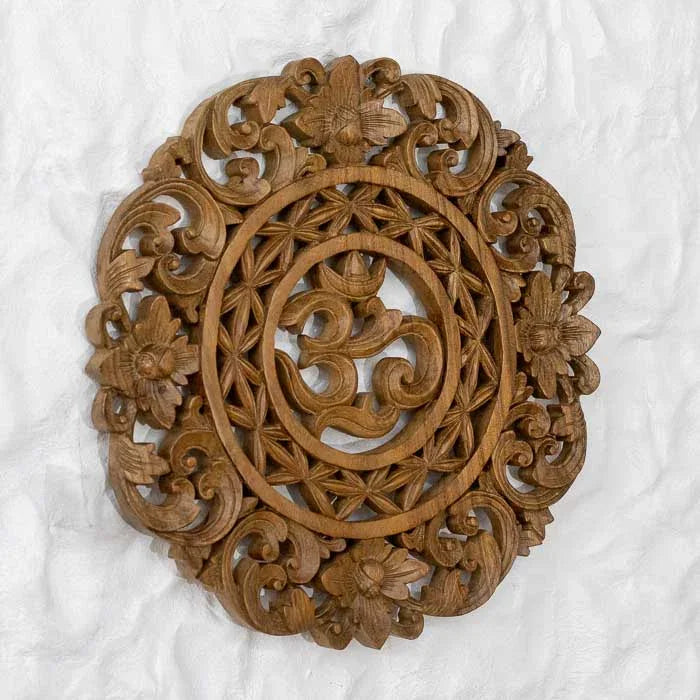 Peça espiritual de parede com símbolo Om cercado por desenhos florais. 