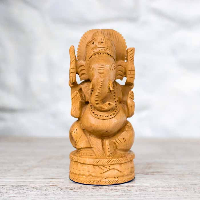 Esculturas de Ganesha em madeira clara entalhada alinhadas por variação de tamanho.