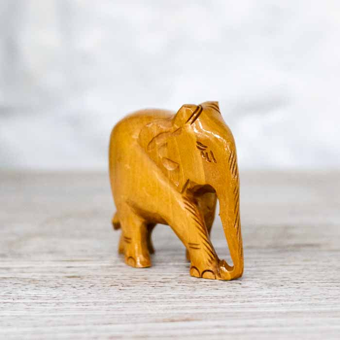 Detalhe da escultura de elefante indiano com a trompa voltada para baixo e orelhas entalhadas.