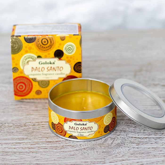 Vela aromática artesanal Goloka em lata metálica amarela estampada com tampa ao lado sobre superfície clara.