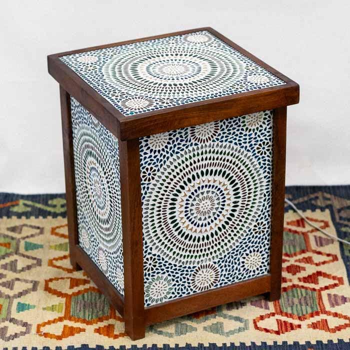 Mesa de apoio iluminada criando um ponto de luz acolhedor sobre tapete ornamental.