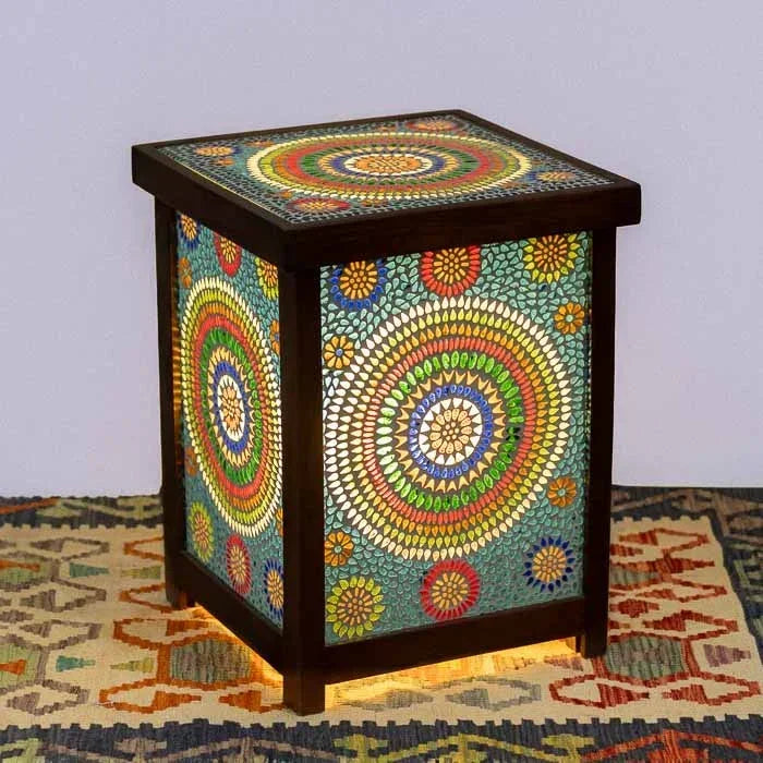 Mesinha lateral indiana em madeira escura com painéis de mosaico de vidro colorido e iluminação interna acesa.