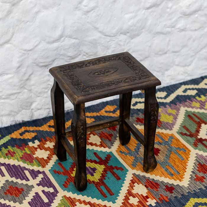 Móvel artesanal indiano de madeira com tampo ornamentado por motivos de flores e folhagens.