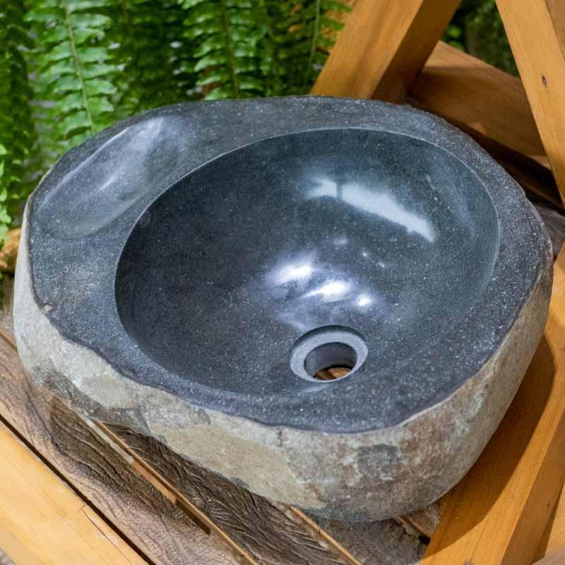 Cuba de pedra natural maciça com exterior rústico, conferindo autenticidade e força mineral à decoração do lavabo.