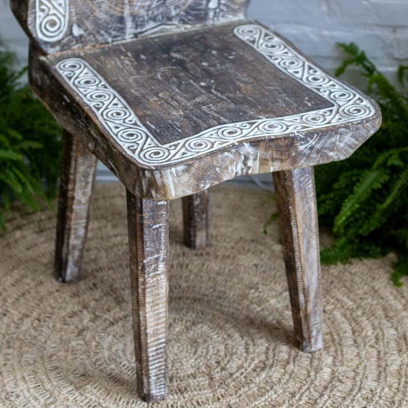 Cadeira de jantar tribal artesanal de Timor esculpida em prancha única de madeira com entalhes em espiral branca.