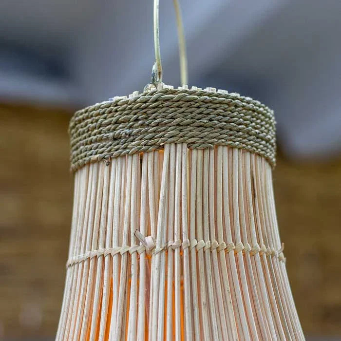 Luminária pendente de rattan clara com acabamento em fibra usada para iluminar salas com estética boho e natural.
