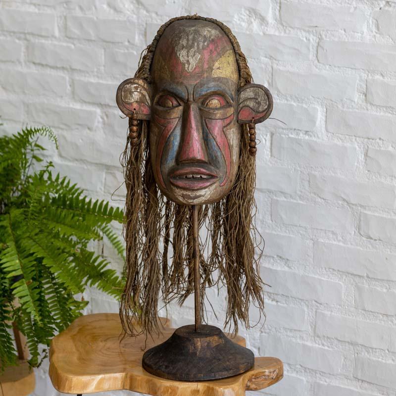 Objeto de arte mística: máscara tribal em madeira Albizia com suporte, ideal para compor nichos e estantes. 