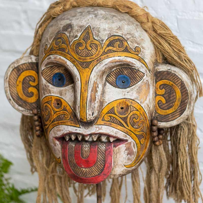 Detalhe dos grafismos étnicos e da pintura vibrante em máscara artesanal de estilo primitivo importada da Indonésia.