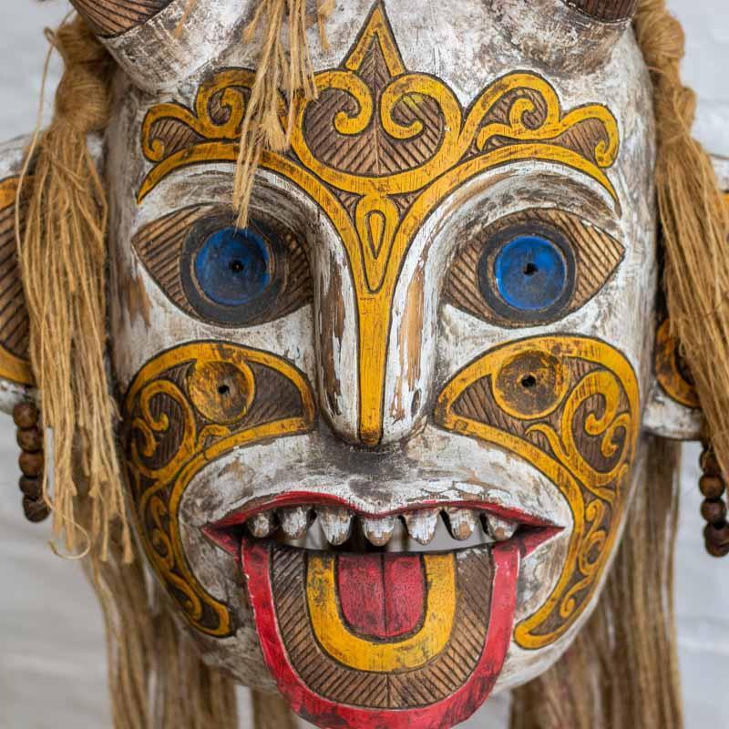 Vista frontal de máscara Kalimantan destacando a fisionomia marcante e o trabalho de entalhe manual detalhado.