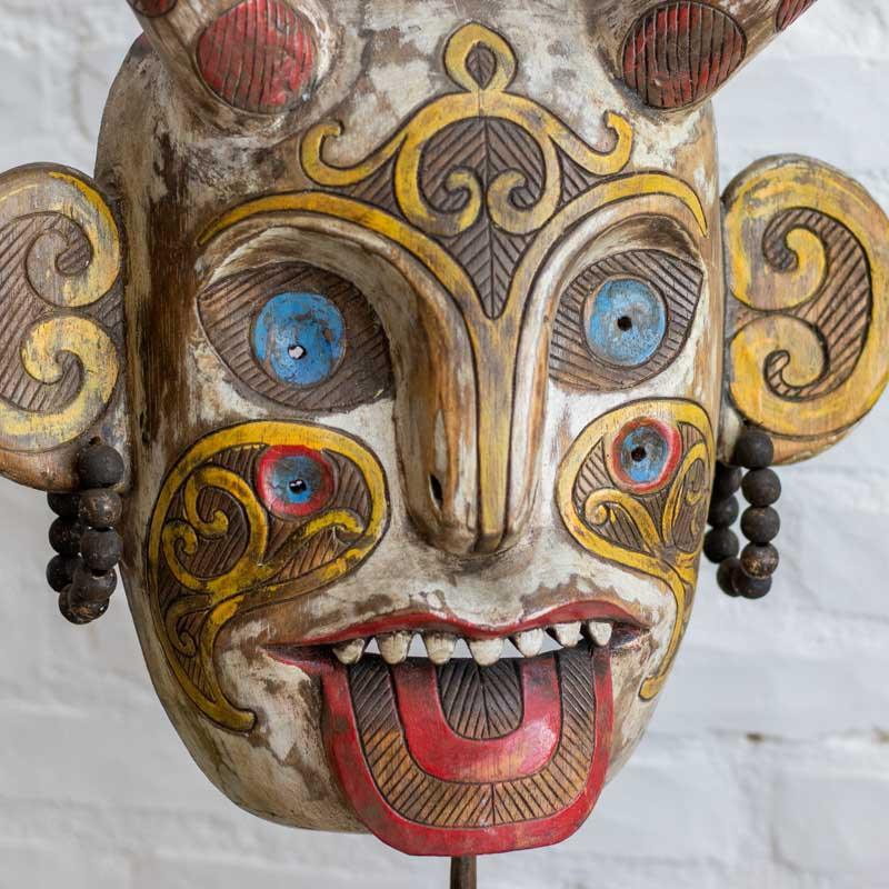 Máscara rústica colorida sobre base, unindo o misticismo de Kalimantan à sofisticação da decoração contemporânea.