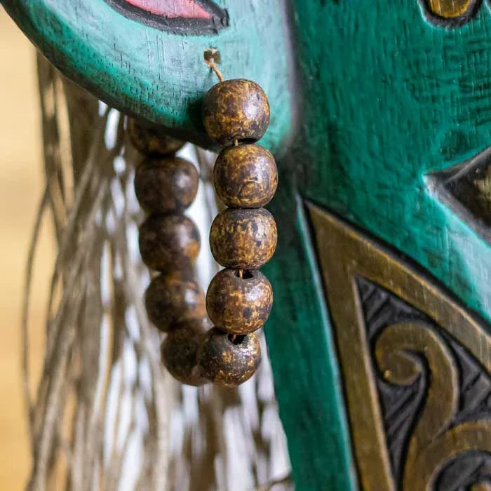 Máscara Borneo sobre pedestal com simbolismo espiritual e cultural. 