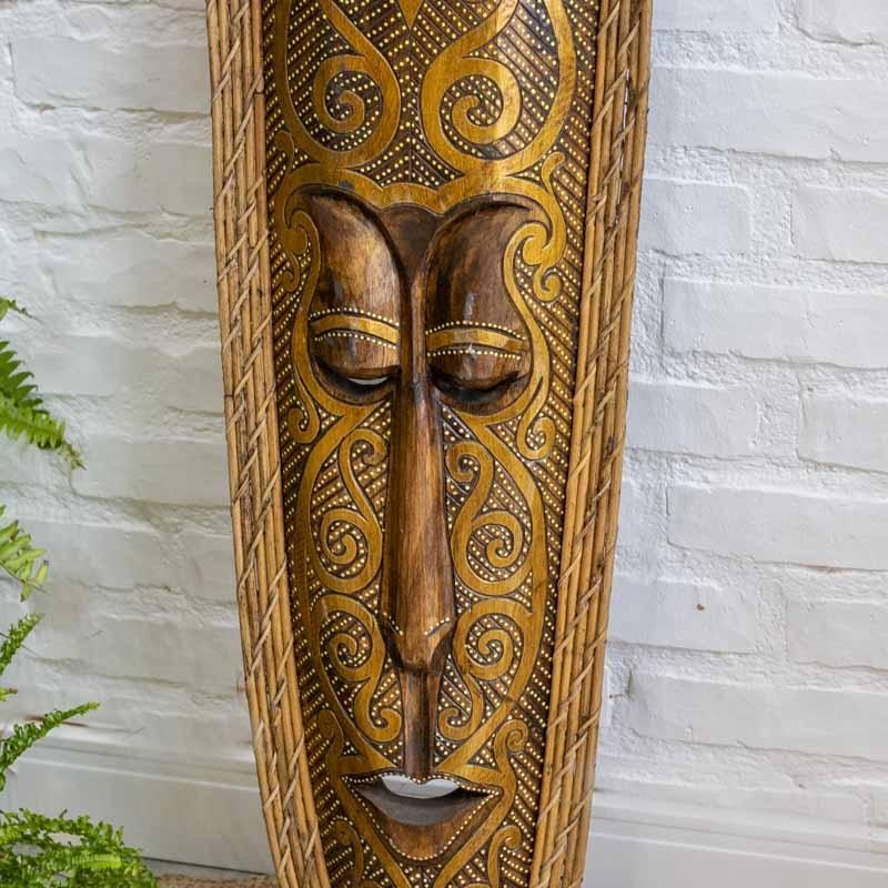 Detalhe dos grafismos étnicos e pontos de pátina branca em máscara decorativa de madeira inspirada na cultura de Bornéu. 