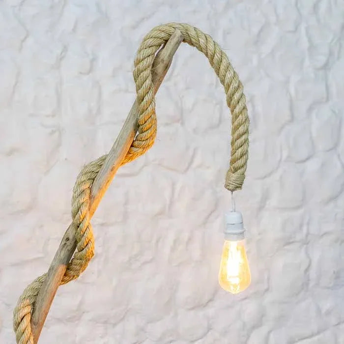 Artefato luminoso artesanal com base sólida de cepo e ramificação superior em curva suave. 